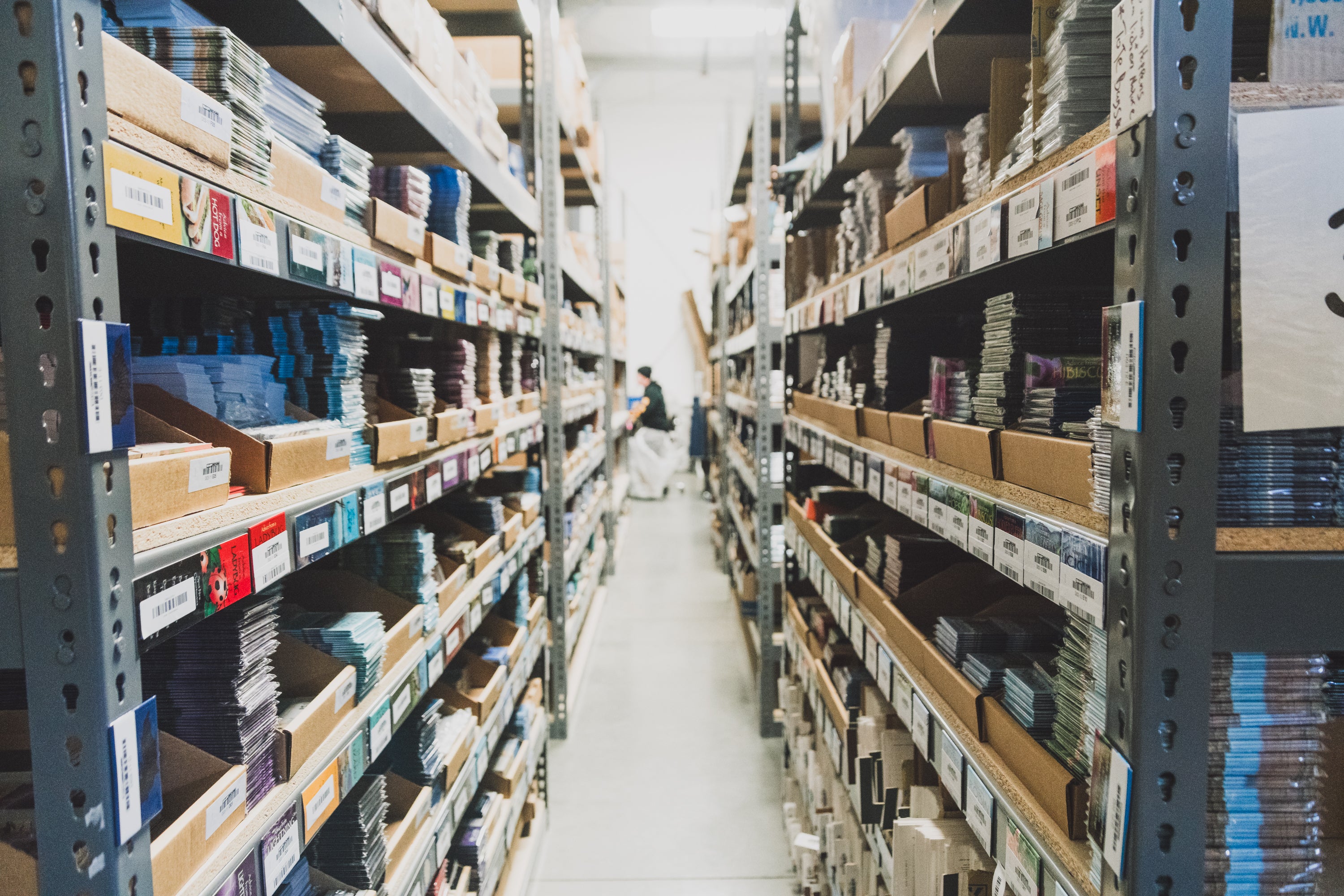 Aisle view inside the Collective Pallet warehouse featuring organized inventory shelving, labeled products, and storage bins prepared for ecommerce order fulfillment.