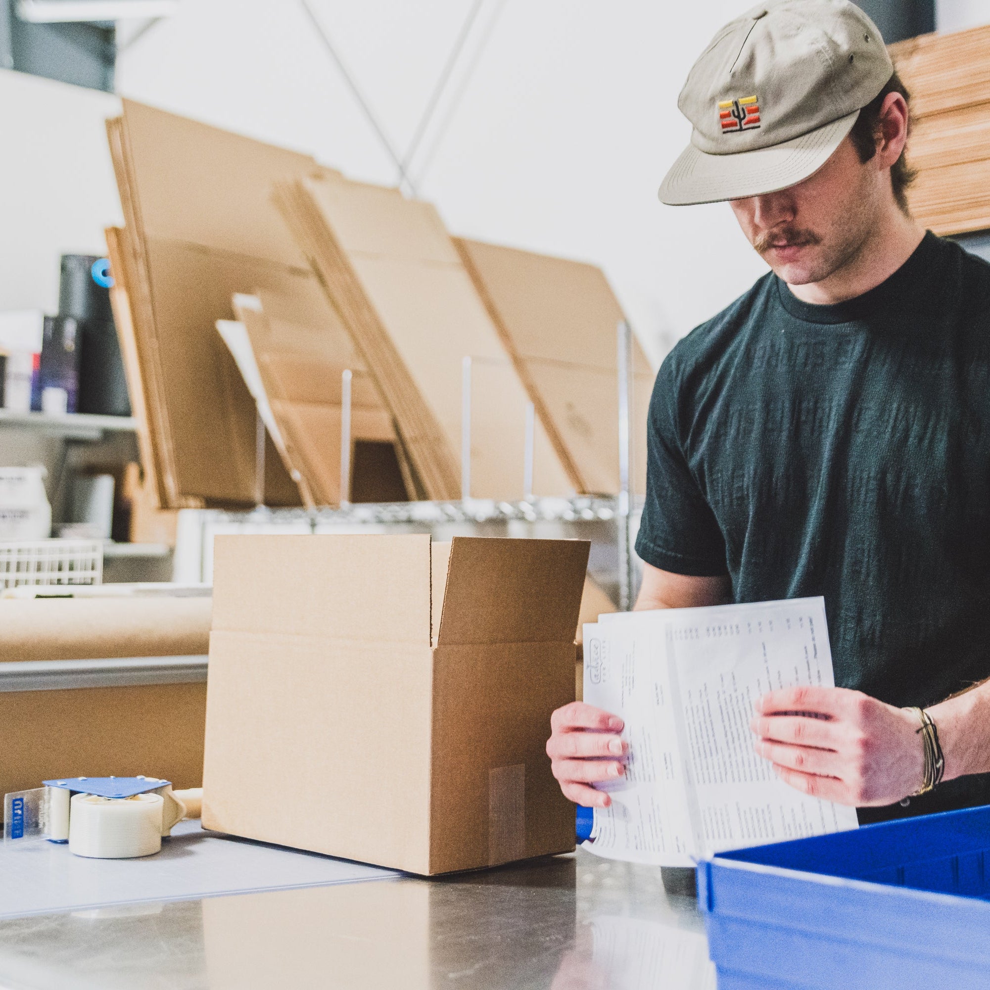 Collective Pallet team member processing returned inventory at a warehouse packing station with shipping materials, order paperwork, and fulfillment supplies.