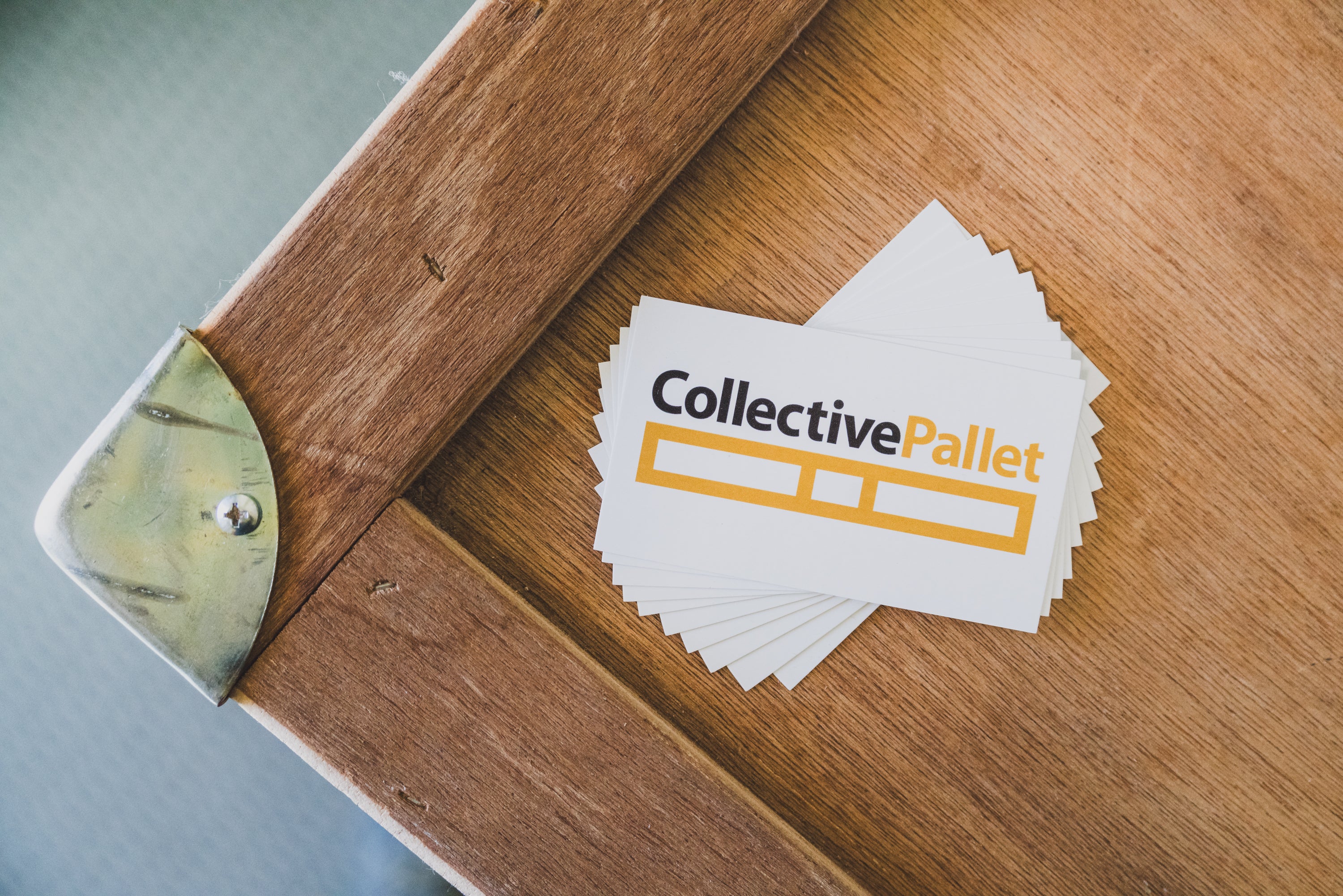 Collective Pallet branded business cards displayed on a wooden surface, highlighting the company’s professional and community-focused fulfillment brand identity.